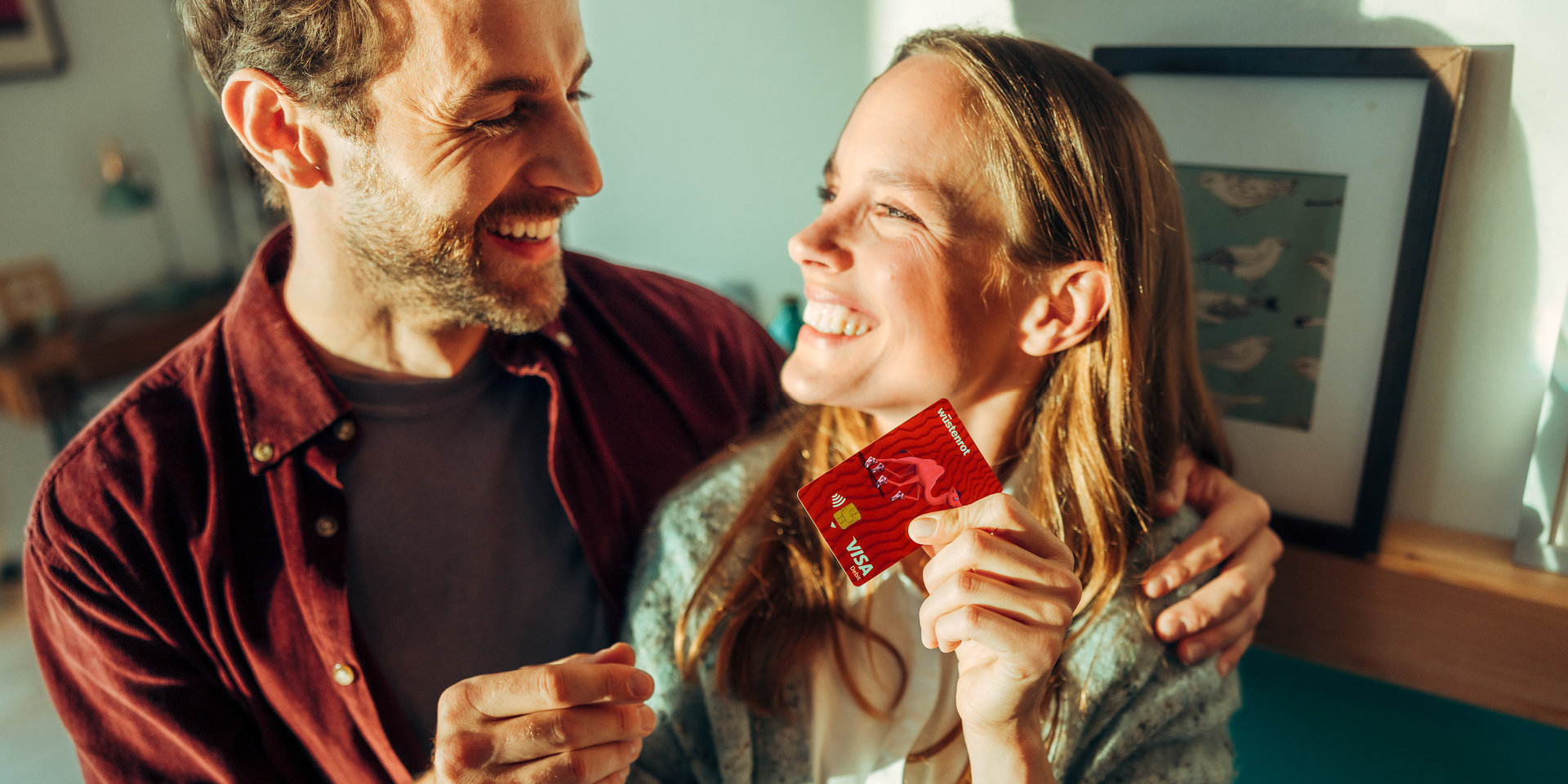 Paar lachend hält Kreditkarte in der Hand Mann und Frau lachend mit Wüstenrot Visa Karte