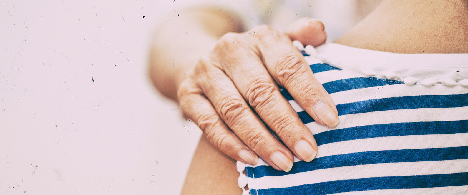 Eine Person legt einer anderen Person die Hand an die Schuler.