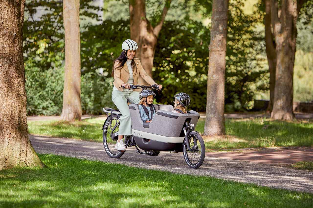 Eine Frau transportiert zwei Kinder mit einem elektrischen Lastenrad